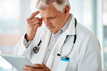 Image showing Happy mature male doctor holding a digital tablet. Thinking senior man using a digital tablet to check medical records or results in a hospital