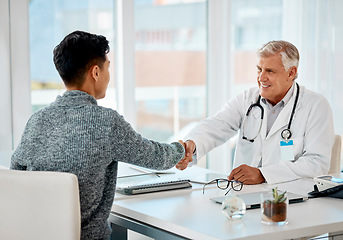 Image showing Mature caucasian doctor greeting a patient with a handshake for a consultation. Senior medical professional smiling in meeting with a patient at the hospital. Two men greeting during a consult