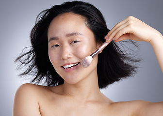 Image showing Apply some powder. a young woman applying makeup against a grey background.