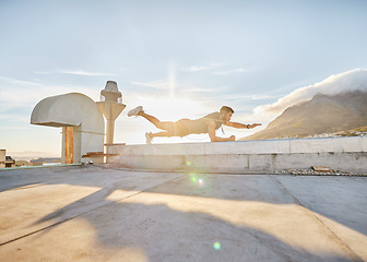 Image showing It time for you discover just how capable you are. a man doing a single-arm plank while on a rooftop.