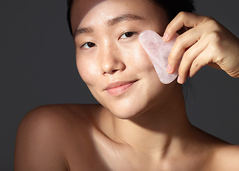 Image showing You dont need go out to get spa results. Studio shot of a beautiful young woman using a scraping tool on her face.