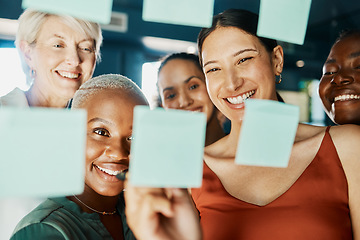 Image showing Its fun coming up with a plan for success. an attractive and diverse group of businesswomen working with sticky notes on a glass wipe board in the boardroom.