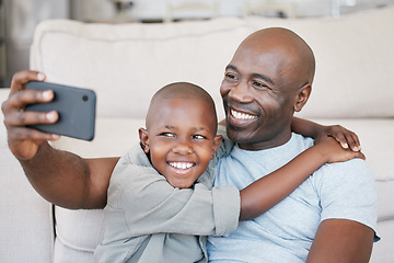 Image showing Being part of a family means smiling for photos. a father and son using a cellphone on the sofa at home.