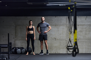 Image showing Muscular man and fit woman in a conversation before commencing their training session in a modern gym.