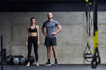 Image showing Muscular man and fit woman in a conversation before commencing their training session in a modern gym.