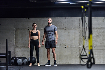 Image showing Muscular man and fit woman in a conversation before commencing their training session in a modern gym.