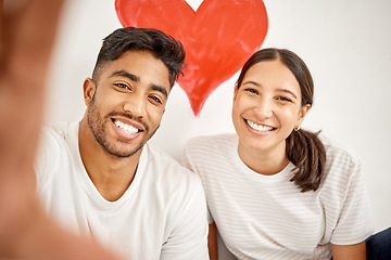 Image showing Love lives right here. a young couple taking a selfie with a red heart in the background.