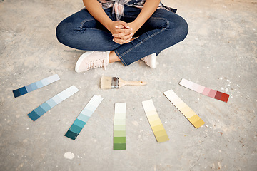 Image showing Can you help me decide on a colour. an unrecognizable woman sitting on the ground with a paintbrush and colour swatches.