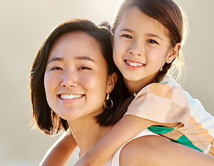 Image showing Growing up to be just like mommy. Cropped portrait of an attractive young woman piggybacking her daughter on the beach.