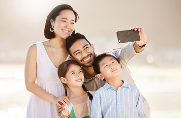 Image showing Summertime selfies. a happy diverse family of four taking selfies at the beach.