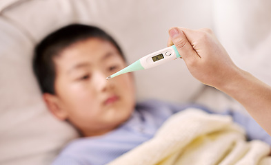 Image showing Looks like your temperature is a little high. a woman checking her sons temperature with a thermometer.