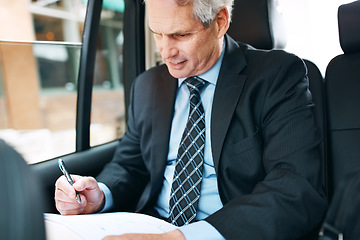 Image showing Places to go and contracts to sign. a mature businessman going through paperwork in the back seat of a car.