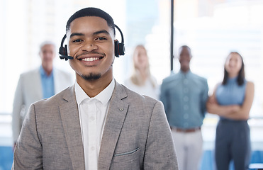 Image showing Customer support superheroes at your service. Portrait of a young businessman using a headset in a modern office with his team in the background.