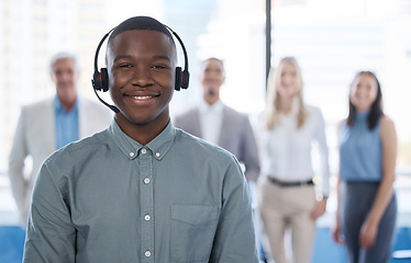 Image showing Let our team handle it. Portrait of a young businessman using a headset in a modern office with his team in the background.