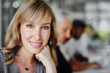 Image showing It feel good to know your worth. Portrait of a businesswoman sitting in a boardroom meeting with colleagues blurred in the background.