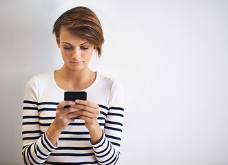 Image showing Lost in mobile conversation. A cropped shot of a beautiful young woman using a smartphone.