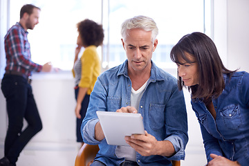 Image showing They might be on to something. two coworkers looking at a digital tablet.