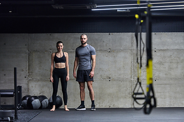 Image showing Muscular man and fit woman in a conversation before commencing their training session in a modern gym.