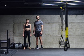 Image showing Muscular man and fit woman in a conversation before commencing their training session in a modern gym.