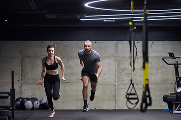 Image showing A fit couple in a modern gym, engaging in running exercises and showcasing their athletic prowess with a dynamic start.