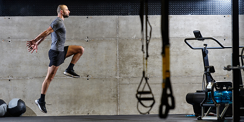 Image showing A muscular man captured in air as he jumps in a modern gym, showcasing his athleticism, power, and determination through a highintensity fitness routine