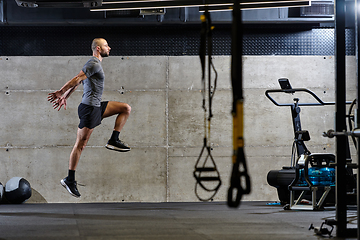 Image showing A muscular man captured in air as he jumps in a modern gym, showcasing his athleticism, power, and determination through a highintensity fitness routine