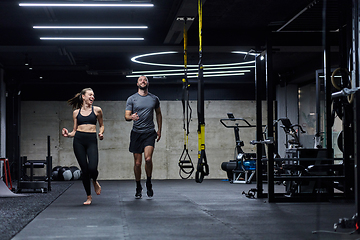 Image showing A fit couple in a modern gym, engaging in running exercises and showcasing their athletic prowess with a dynamic start.