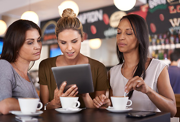 Image showing Discussing my business plan with the girls. Three attractive young women gathered around a tablet pc in a restaurant.