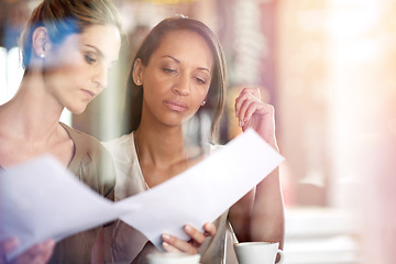 Image showing Getting down to business with coffee. Two women discussing paperwork during a business meeting at a cafe.