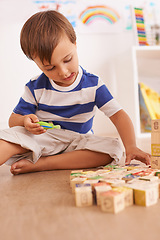 Image showing Learning through play. a young boy playing with his building blocks in his room.