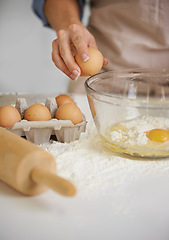 Image showing To make a cake you have to break a few eggs. Closeup shot of a woman putting ingredients into a bowl in her kitchen.