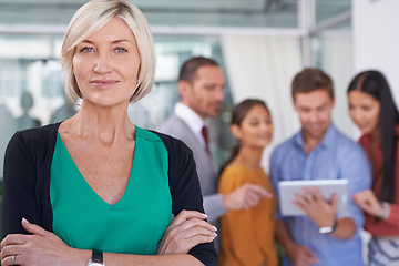 Image showing True leaders dont create followers... They create more leaders. A portrait of a middle-aged businesswoman standing in an office with her coworkers in the background.