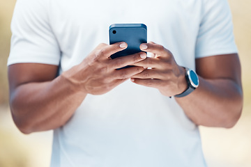 Image showing Closeup of a mixed race unknown male using his smartphone outside before a workout. Unknown ethnic male send a text using his wireless device outdoors