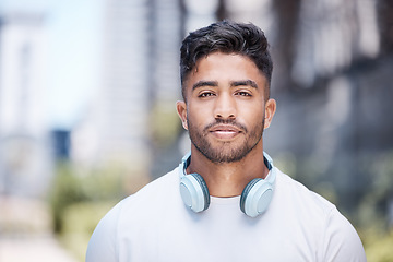 Image showing Serious fitness man wearing headphones around his neck while looking at the camera. Dedicated male runner out in the city for a workout