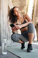 Image showing I love seeing good health stats. Full length shot of an attractive young woman crouching down and using her cellphone during her outdoor workout.