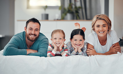 Image showing Portrait of a smiling young caucasian family lying close together on the bed at home. Happy adorable girls bonding with their mother and father on a weekend. Happy couple and daughters in the morning