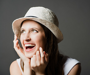 Image showing Nothing completes an outfit like a hat. a young woman day dreaming against a studio background.