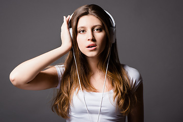 Image showing Music is art that speaks to the heart. a young woman listening to music against a studio background.