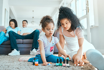 Image showing Tell them to keep the dolls. two sister playing on the floor while their parents relax in the background.