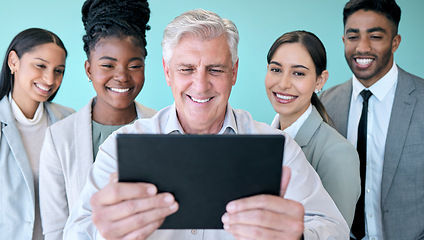 Image showing Snapping pics with the team. Studio shot of a diverse group of corporate businesspeople using a tablet to take selfies against a blue background.