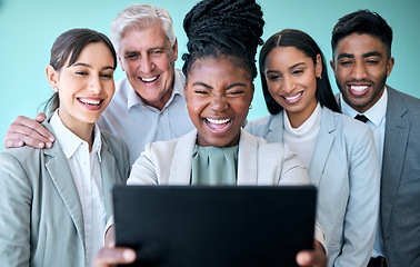 Image showing Their relationship goes beyond business. Studio shot of a diverse group of corporate businesspeople using a tablet to take selfies against a blue background.