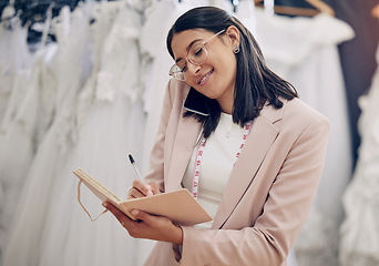 Image showing Ill put you down for a fitting. an attractive young seamstress writing notes while talking on her cellphone.