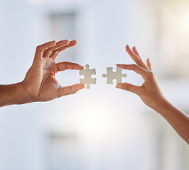 Image showing Maybe we can solve it together. two unrecognizable businesspeople holding puzzle pieces at work.