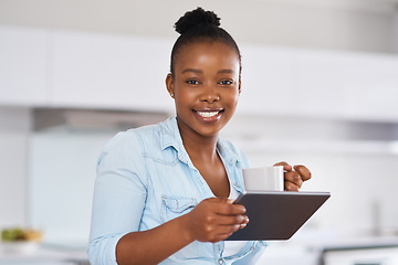Image showing Staying in the know is easy with the internet. a woman drinking coffee while using a digital tablet at home.