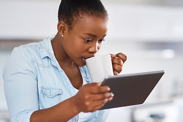 Image showing Spilling some tea on social media. a woman drinking coffee while using a digital tablet at home.