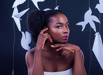 Image showing Unleash your inner sparkle. Studio portrait of a beautiful young woman posing with paper birds against a black background.