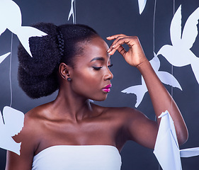 Image showing With brave wings, she flies. Studio shot of a beautiful young woman posing with paper birds against a black background.