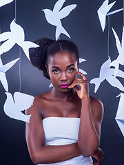 Image showing She radiates with boldness and beauty. Studio portrait of a beautiful young woman posing with paper birds against a black background.