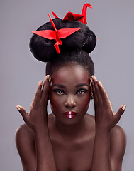 Image showing Theres boundless creativity with makeup. Studio portrait of a beautiful young woman wearing Asian inspired makeup and posing with origami against a grey background.