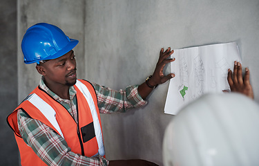 Image showing Teamwork makes the construction project work. a young man and woman going over building plans at a construction site.